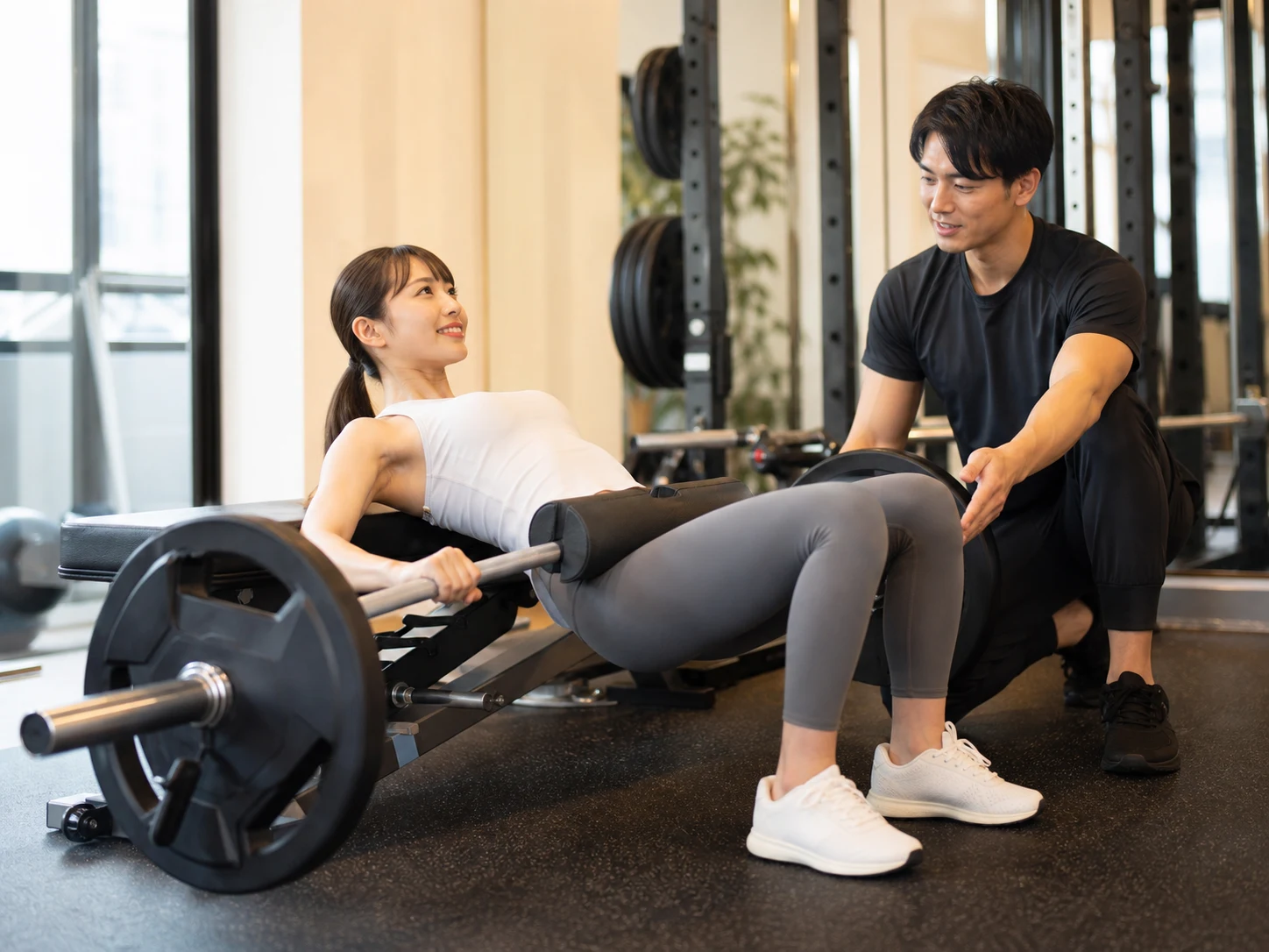 トレーナーの指導でヒップスラストに取り組む女性